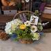 A spring gift basket full of faux flowers with a birch bark Easter bunny gift tag tied to the top.